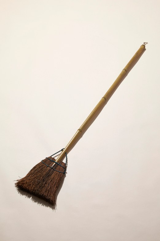 Traditional Japanese bamboo broom with natural bristles and wire binding against neutral background