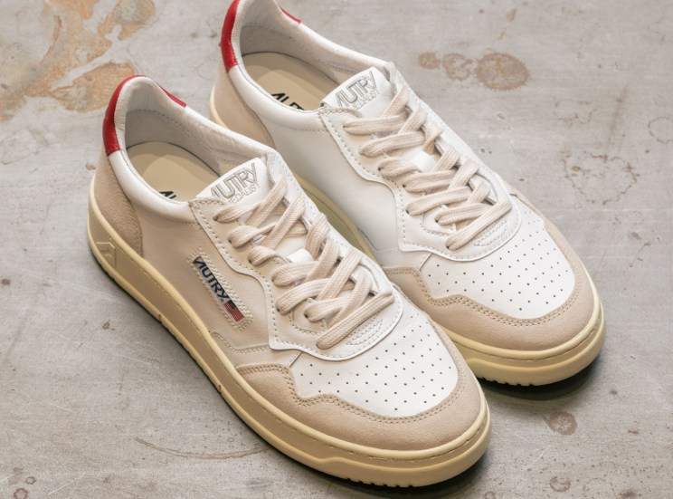 Cream and beige Autry sneakers with red heel detail on concrete floor