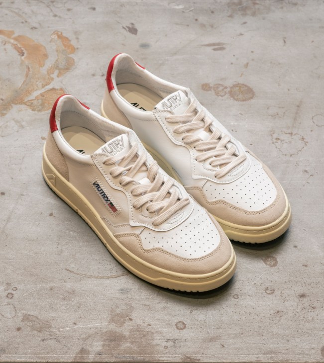 Cream and beige Autry sneakers with red heel detail on concrete floor