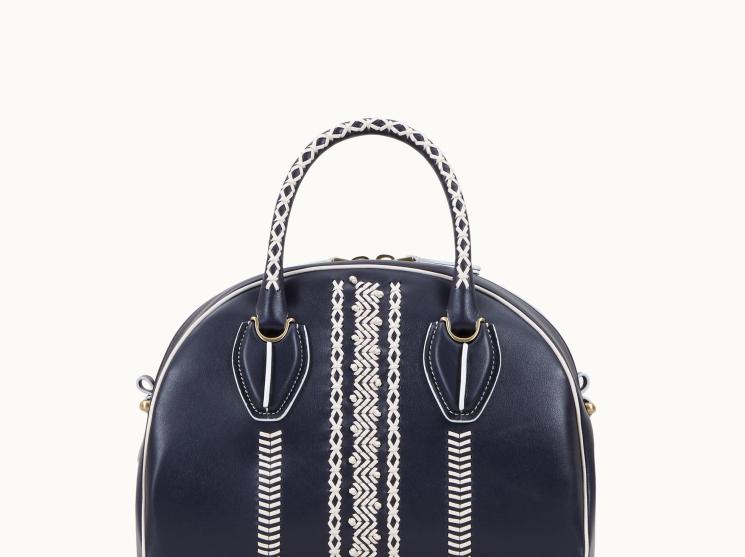 Navy handbag with white geometric hand-stitching detail and patterned handles
