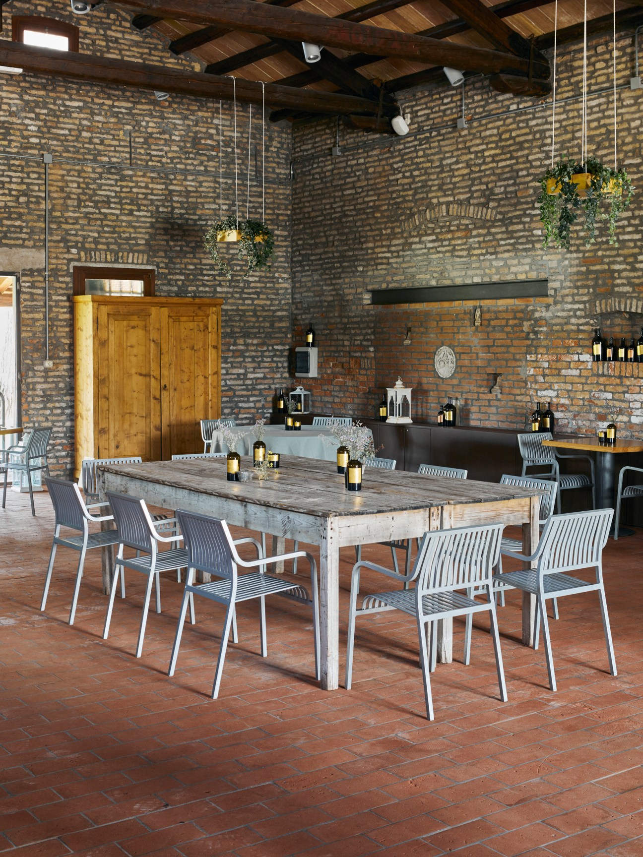 Rustic restaurant interior with exposed brick walls, wooden beams, and modern white chairs around wooden tables