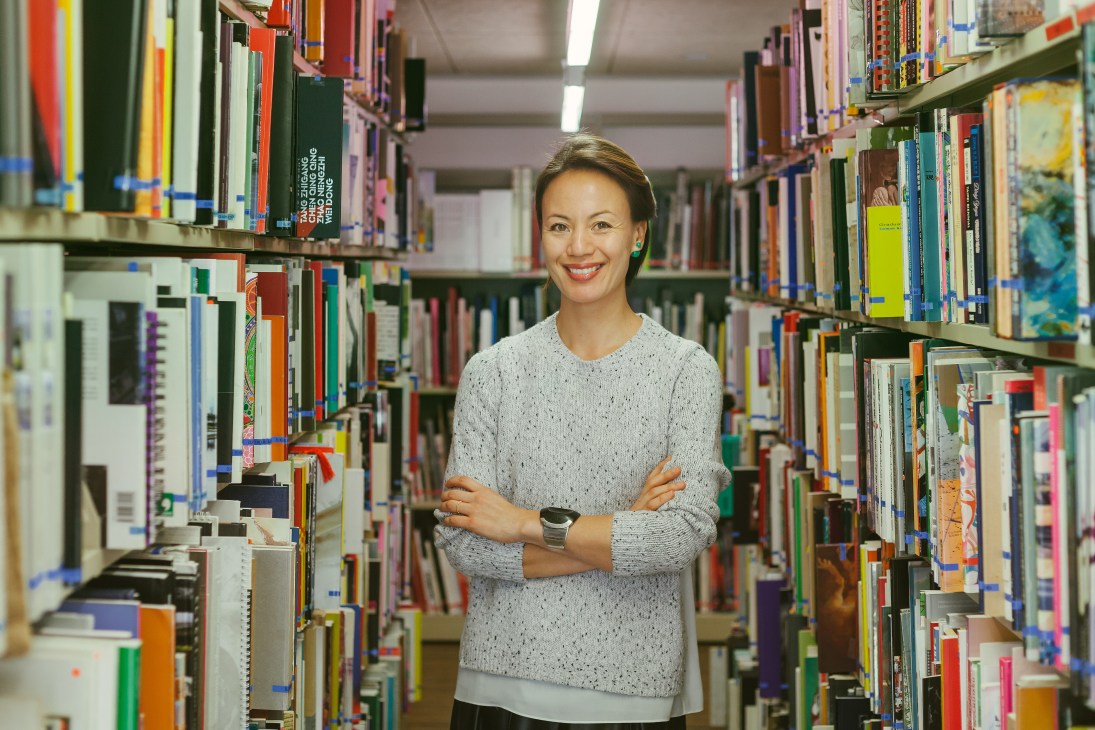 Claire Hsu, co-founder and executive director of the Asia Art Archive, stands in a library surrounded by bookshelves.