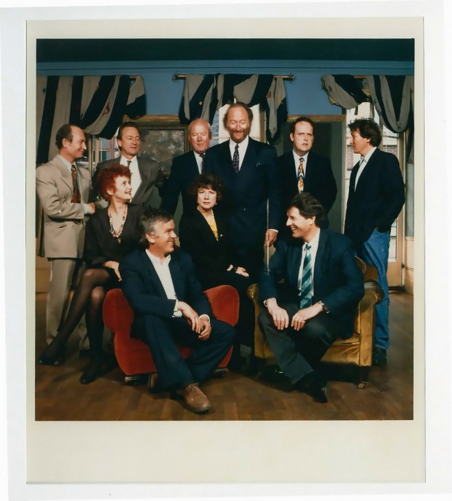 Group of men and women in business attire posing together in an elegant room with Tudor-style beams
