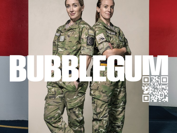 Two female soldiers in camouflage uniforms standing back-to-back with 'BUBBLEGUM' text and QR code overlay