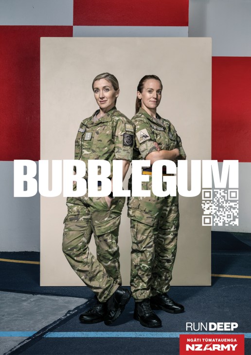Two female soldiers in camouflage uniforms standing back-to-back with 'BUBBLEGUM' text and QR code overlay