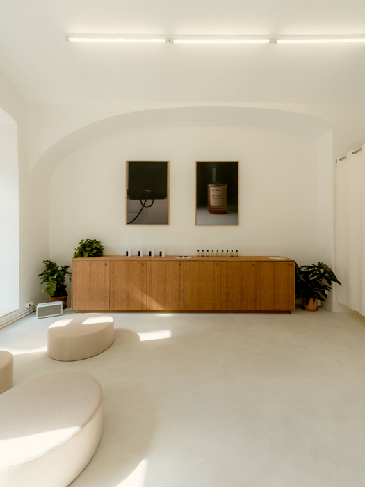 Minimalist retail interior with white walls, wooden sideboard, artwork, and modern lighting
