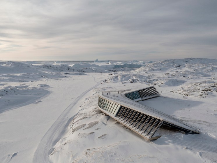Snow-covered modern building with angular roof emerging from white landscape in Greenland