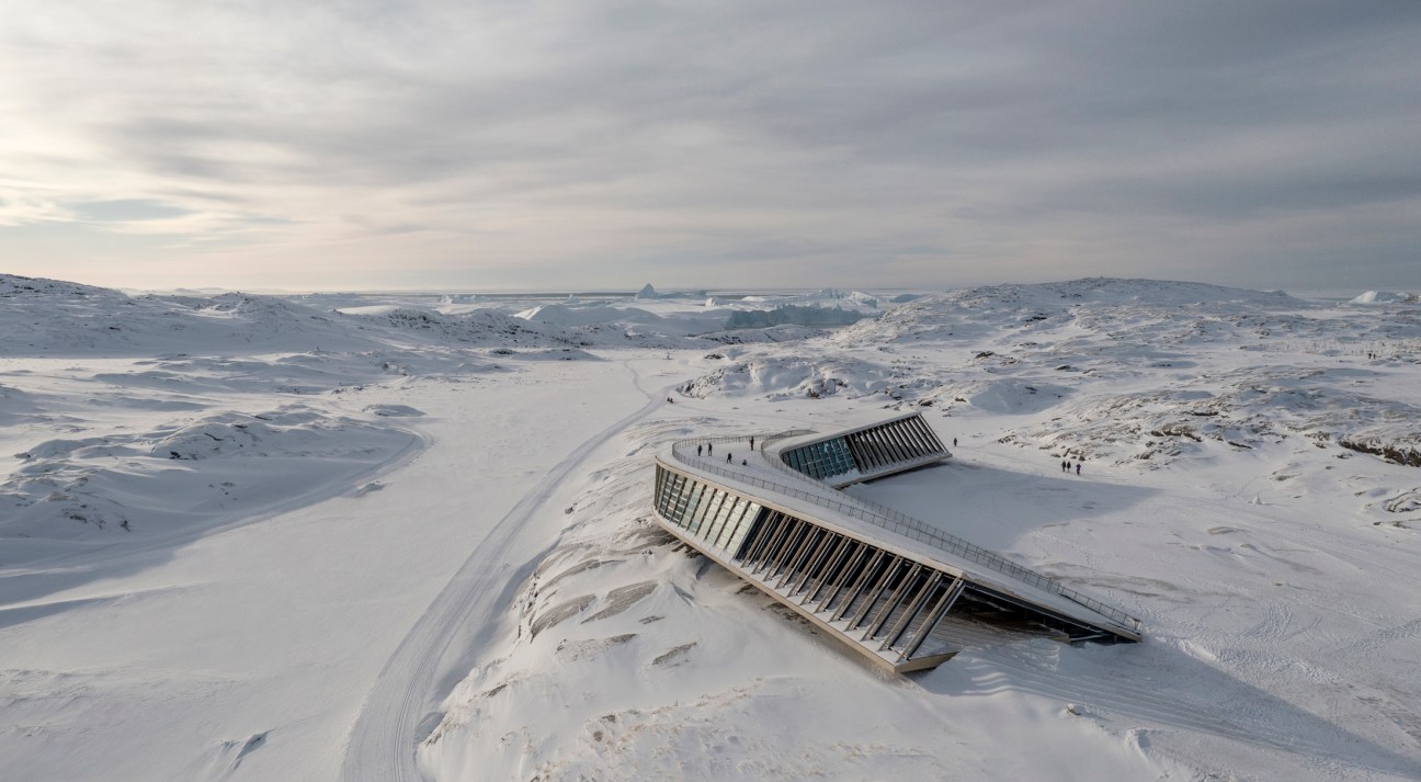 Snow-covered modern building with angular roof emerging from white landscape in Greenland