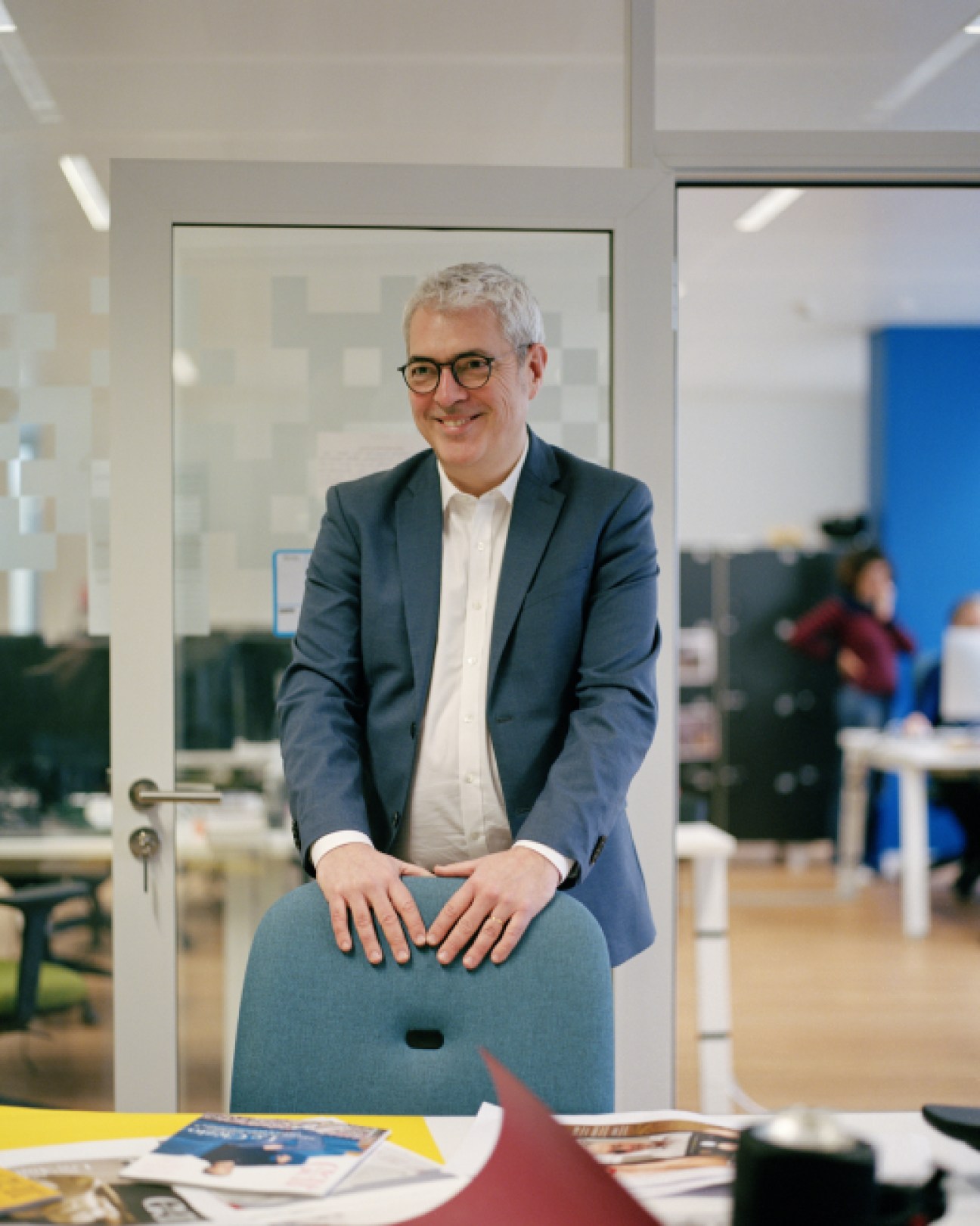 Lomig Guillo, editor in chief of JDD Magazine, sitting on a blue chair in a modern office