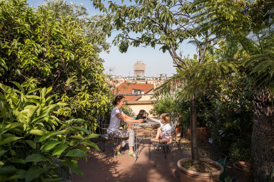 Rooftop terrace with lush greenery, outdoor dining furniture and city skyline view creating natural cooling outdoor living space