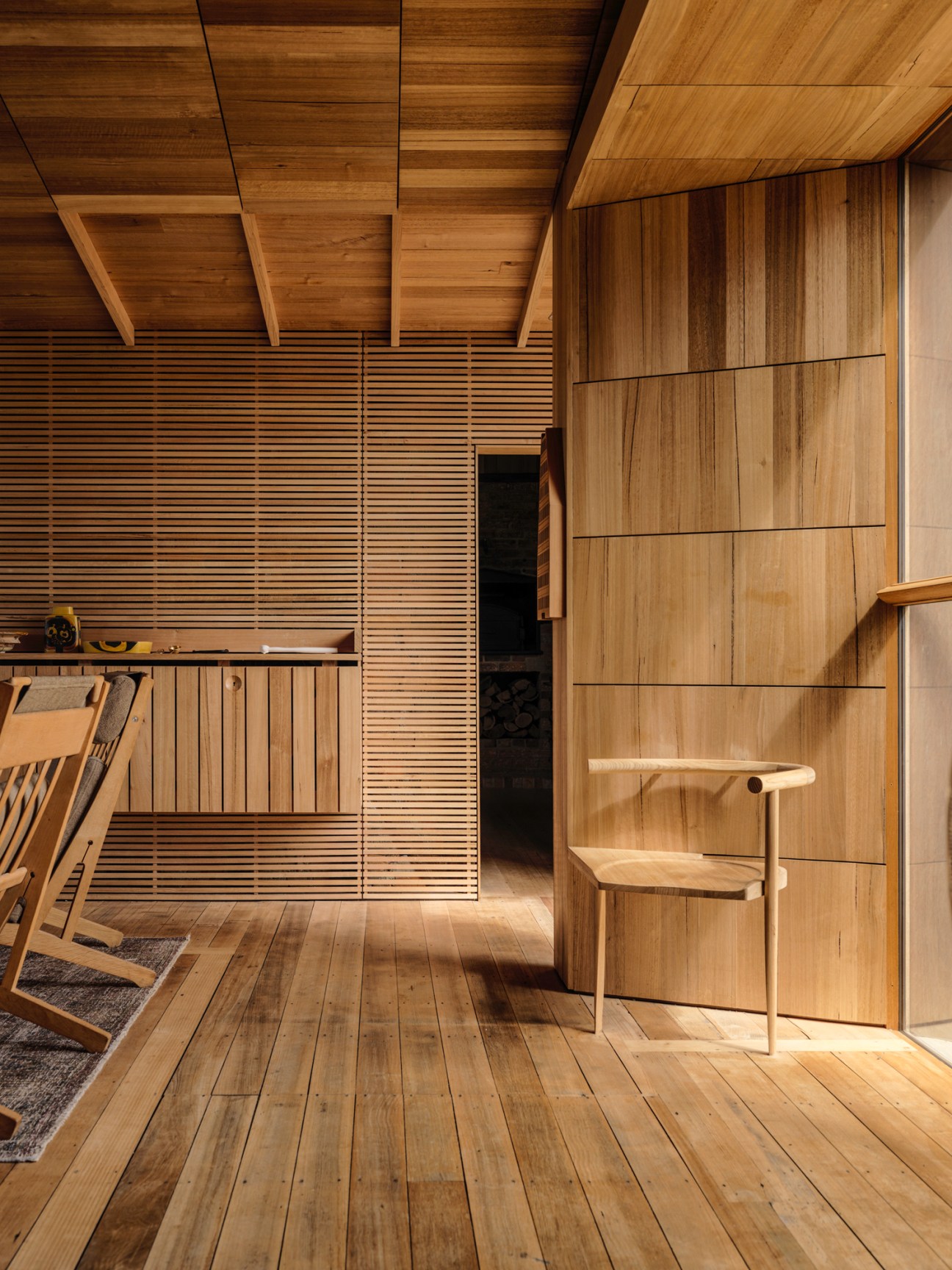 All-wood interior with timber walls, ceiling beams, built-in storage, desk and wooden chair
