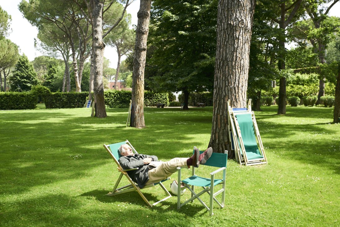 Person resting in a deck chair outdoors on green grass with feet up on a small table