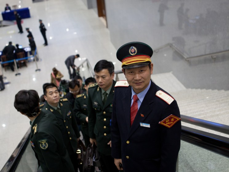 Train conductor and military personnel on an escalator at Haikou railway station