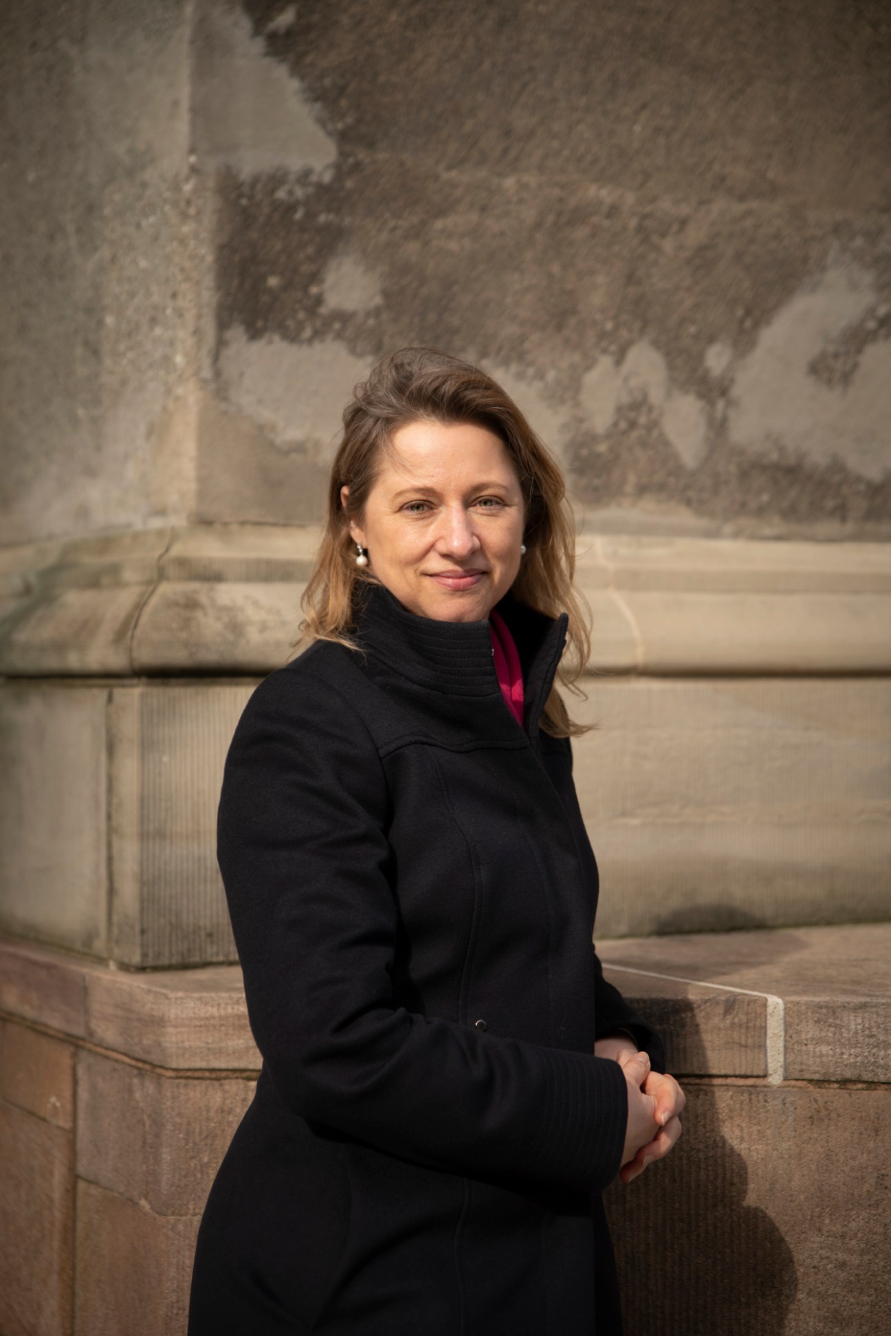 Sophie Haestorp Andersen sitting on stone steps wearing a black coat