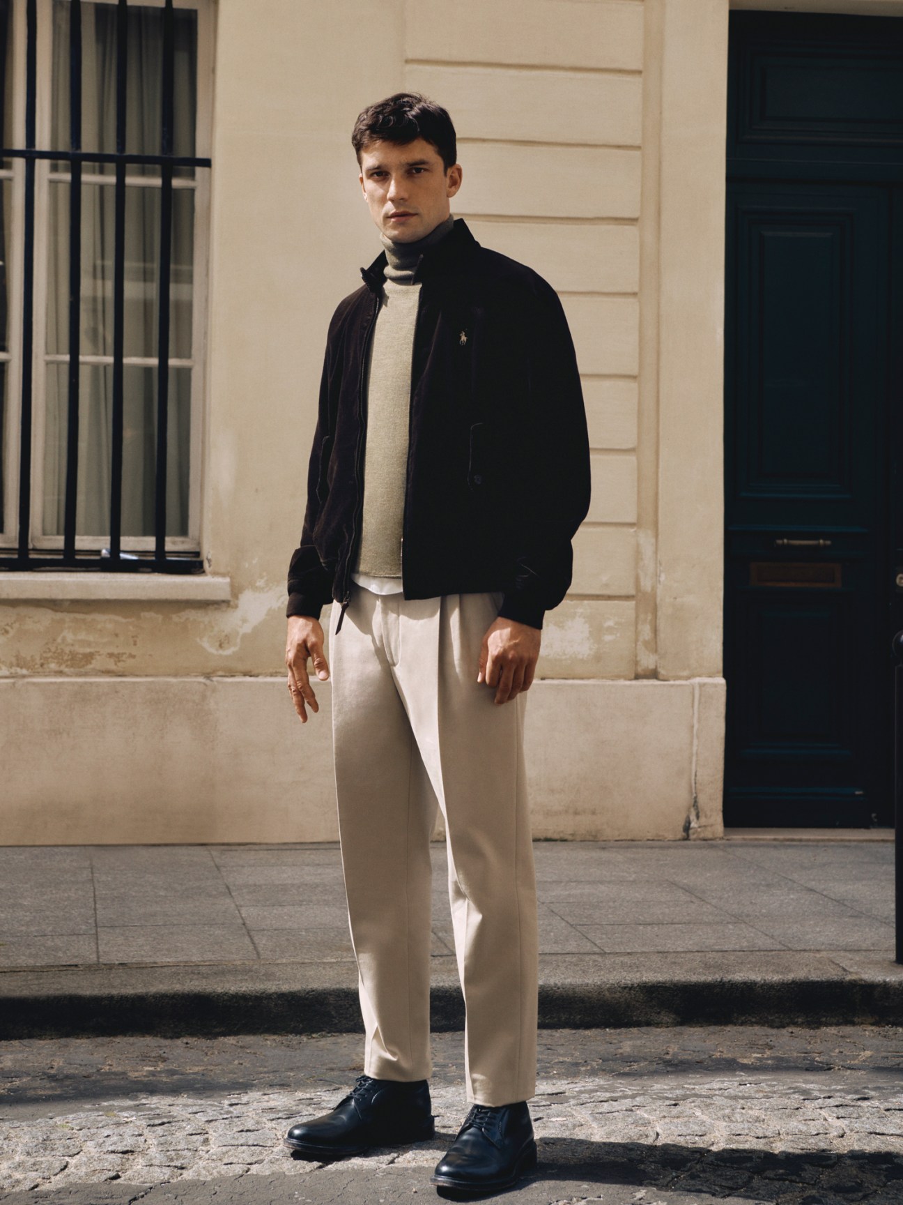 Model wearing navy blazer with cream jumper, white t-shirt and beige trousers with black leather shoes