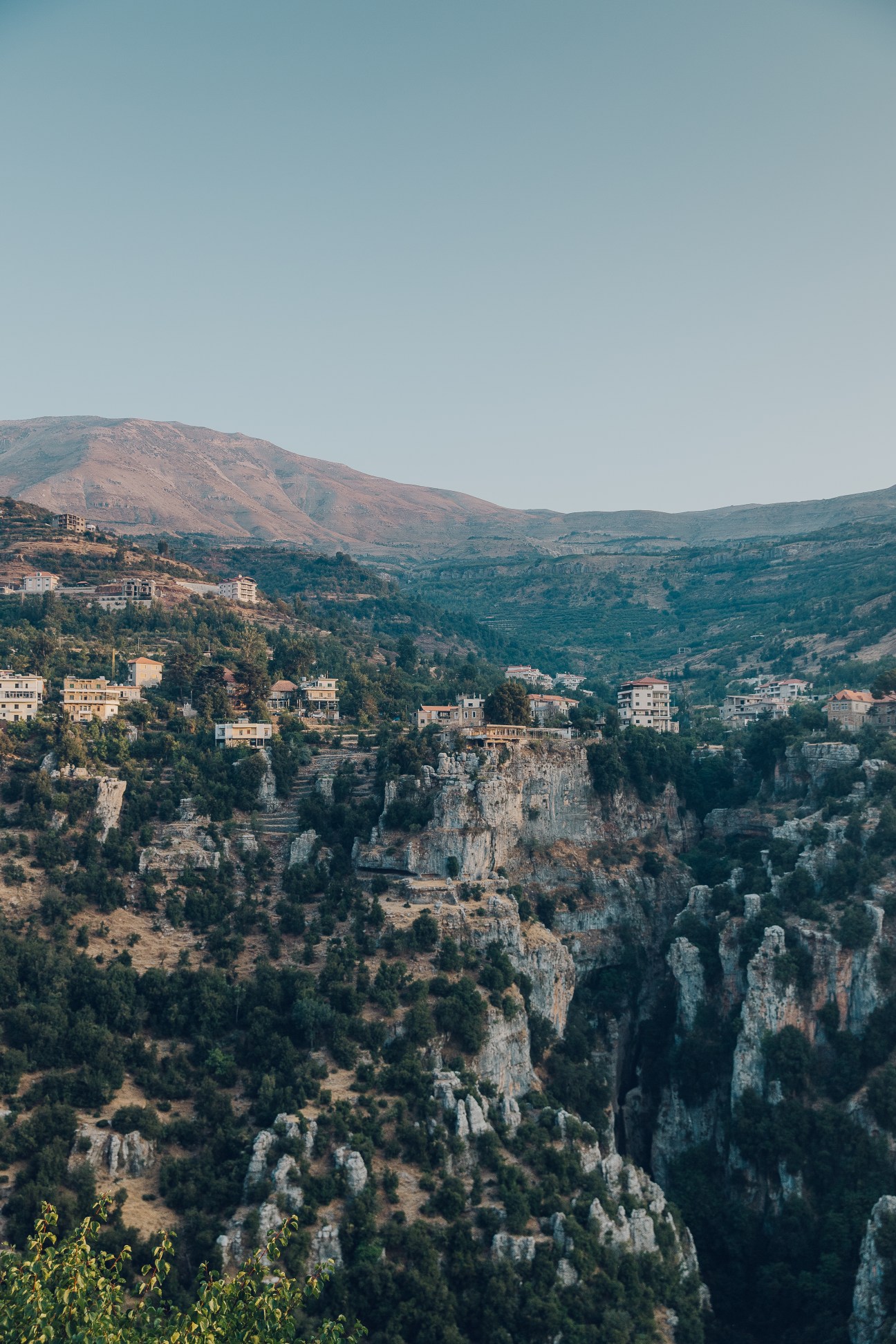 Qadisha Valley gorge with buildings perched on cliffs and mountains in the background, seen from Hasroun village in Lebanon.