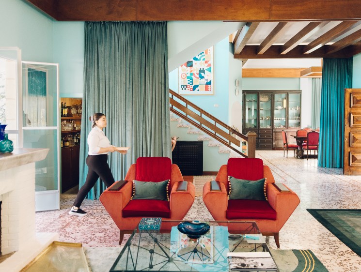 Retro-styled salon with turquoise walls, orange and red mid-century chairs, and wooden beams at Villa Chamoun hotel.