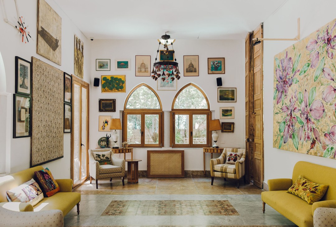 Arthaus lobby with vintage furniture, framed artwork on walls, arched windows, and yellow armchairs.