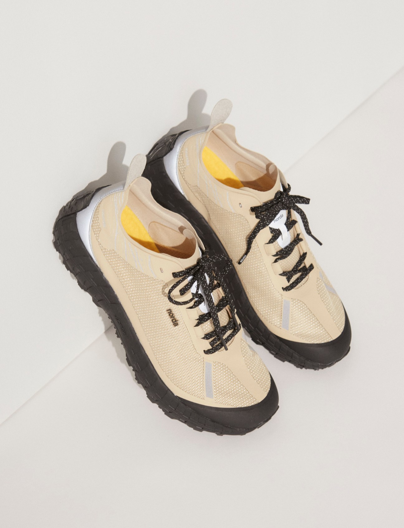 Pair of beige trail running sneakers with black laces and rugged soles