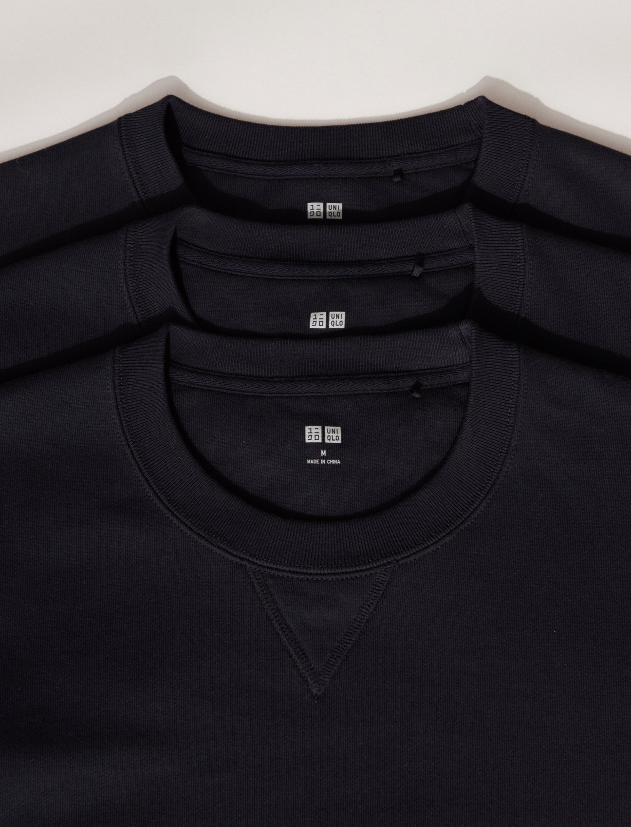Three black Uniqlo sweatshirts stacked and layered showing neck details