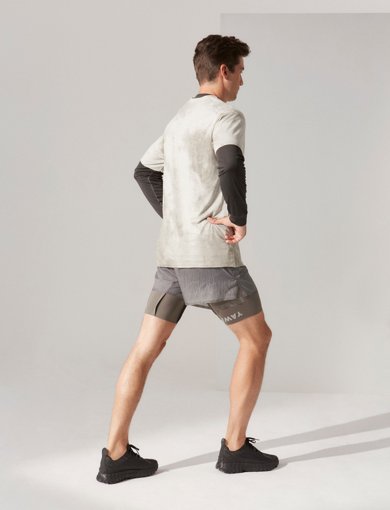 Model in athletic wear with layered t-shirts, shorts and running shoes