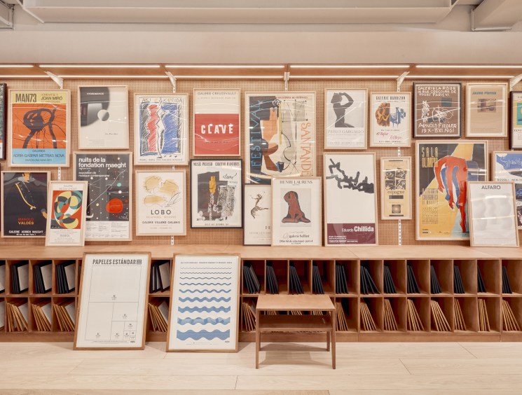 Interior of La Papelería pop-up shop with organized wooden shelving displaying art posters, prints, and paper products