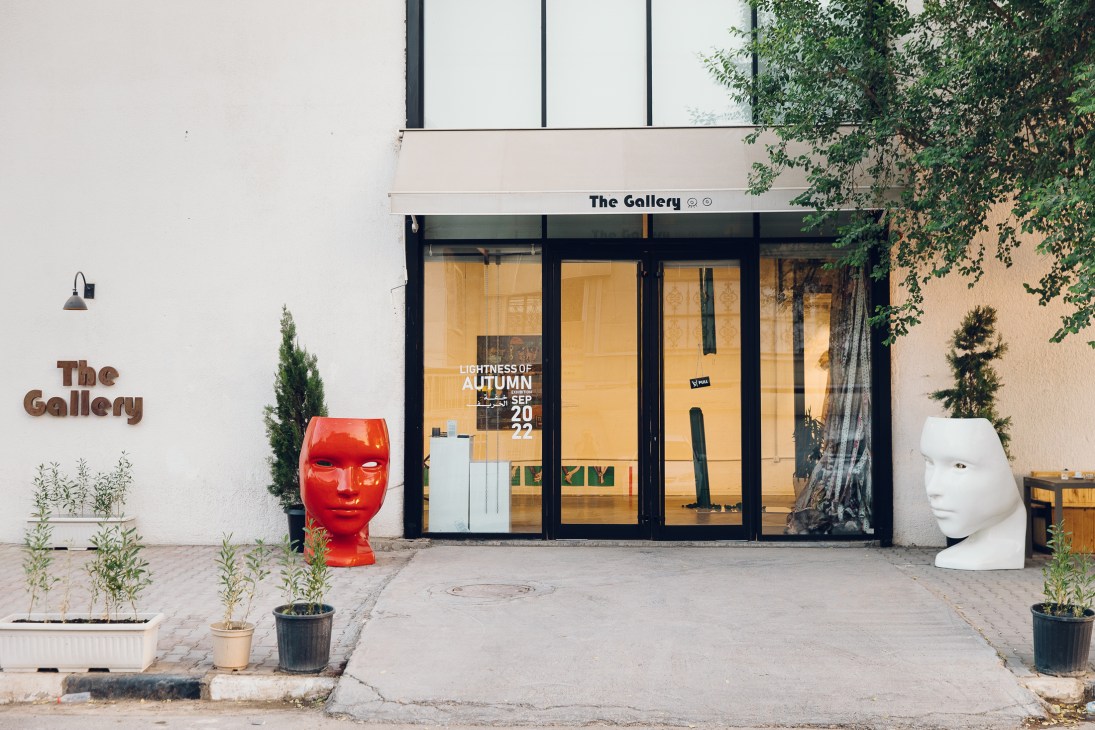 Modern art gallery storefront with red and white sculptural head pieces flanking glass entrance doors