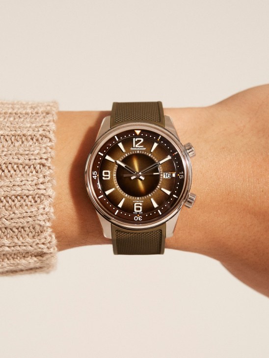 Person wearing bronze Jaeger-LeCoultre Polaris Date watch with green rubber strap and bronze sunburst dial