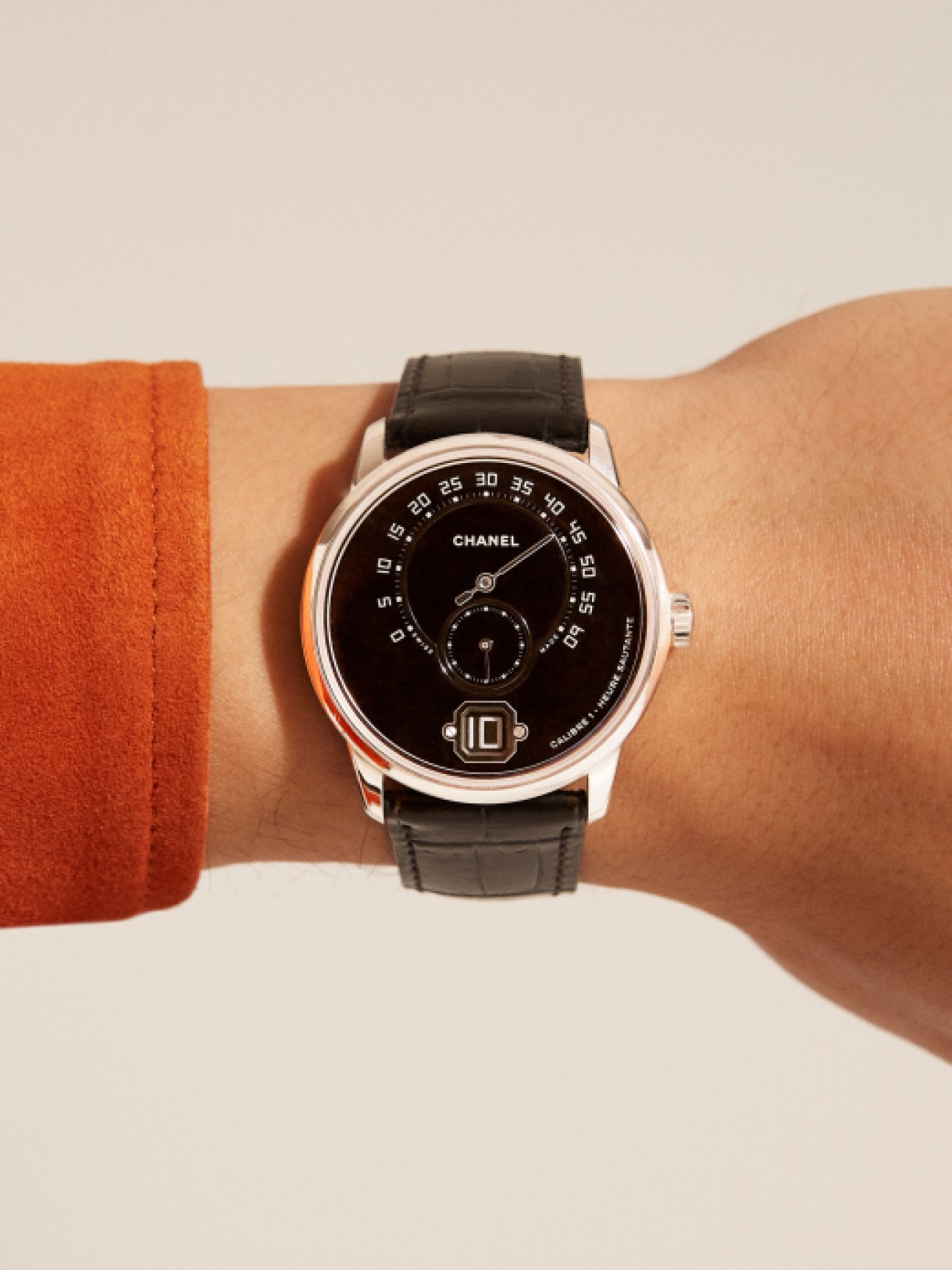 Chanel Monsieur watch with black dial, silver case Roman numerals and leather strap on wrist
