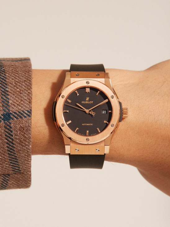 Person wearing rose gold Hublot Classic Fusion watch with black dial and rubber strap on wrist