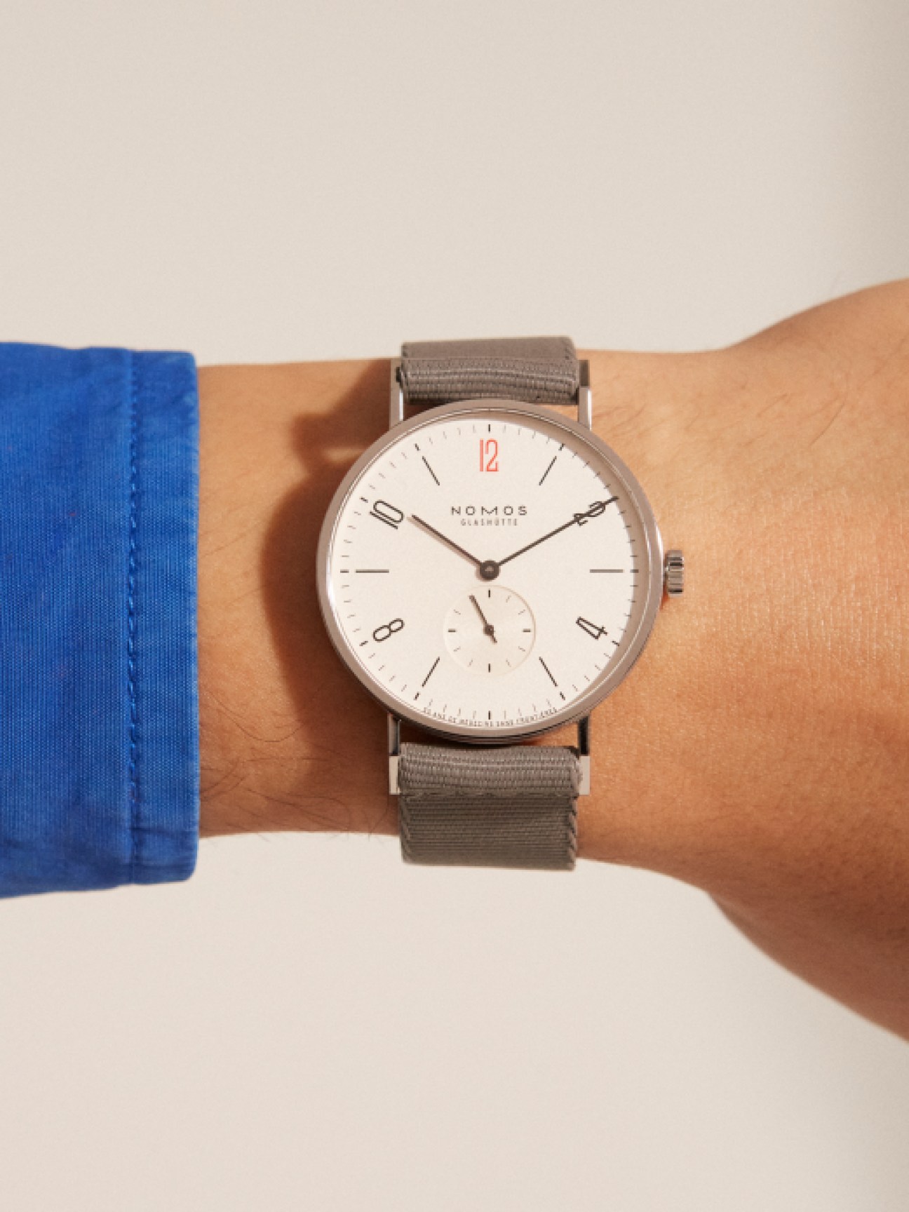 Nomos Glashütte Tangente 38 watch with white dial and gray fabric strap worn on wrist