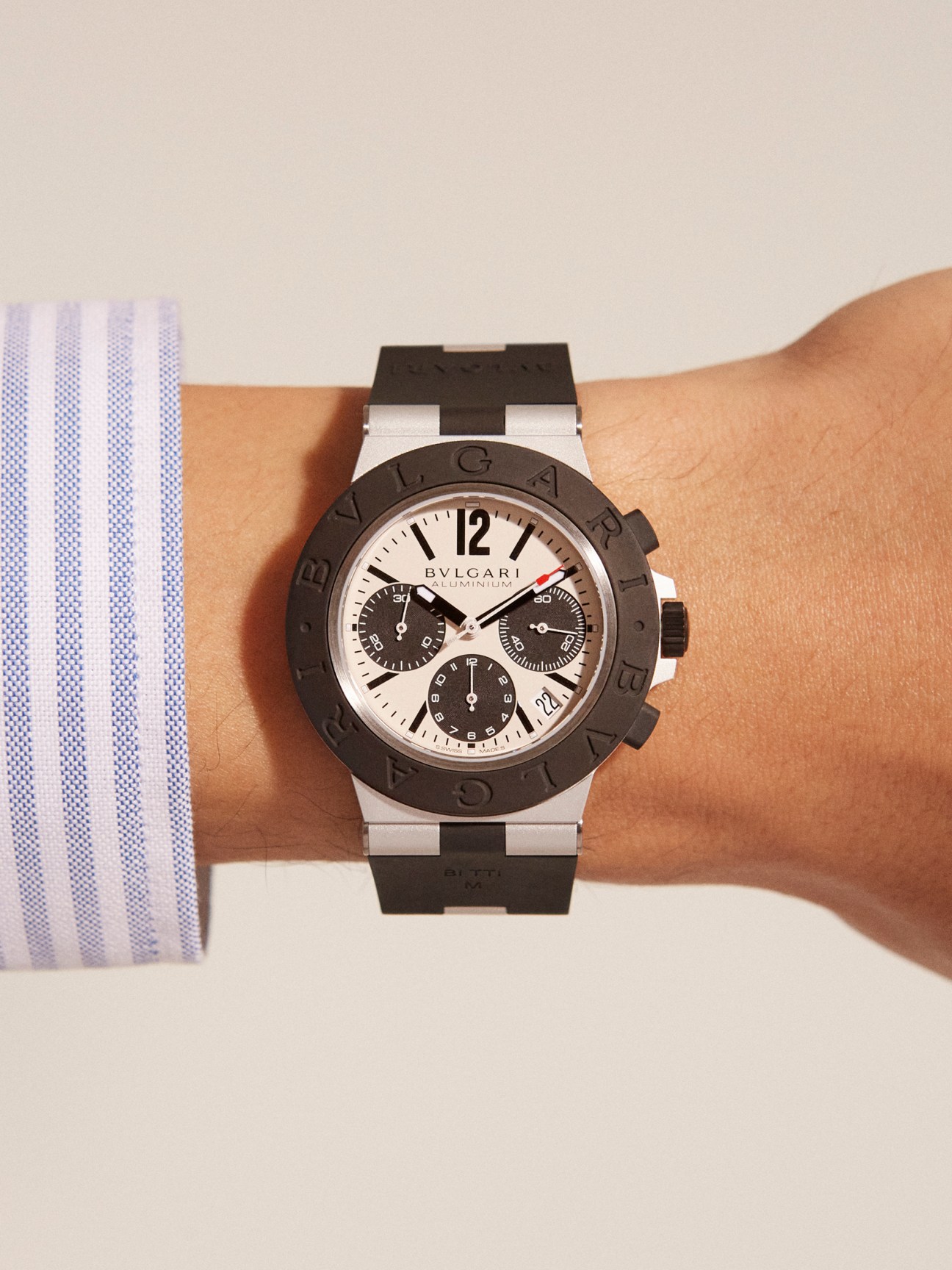 Bulgari aluminium chronograph watch with black rubber strap and white dial worn on wrist.
