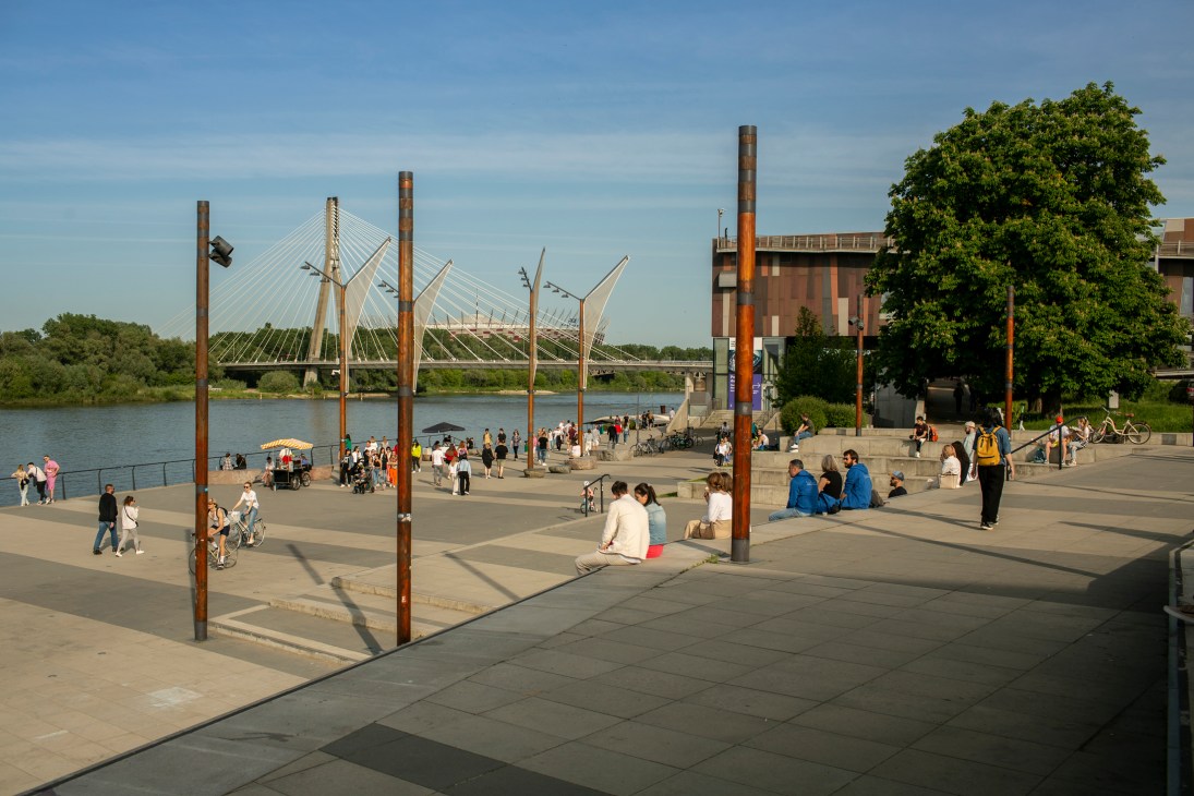 A park scene in Warsaw with people relaxing on grass under trees