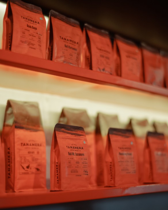 Display of various coffee beans in clear containers showing different roasts and varieties from Indonesian coffee regions