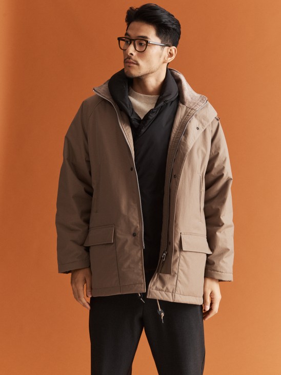Model in layered jacket and vest with glasses
