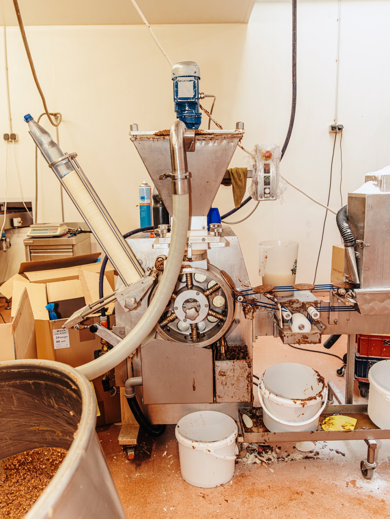 Industrial food processing equipment with conveyor tubes, mixing hoppers and collection buckets in a bakery production facility