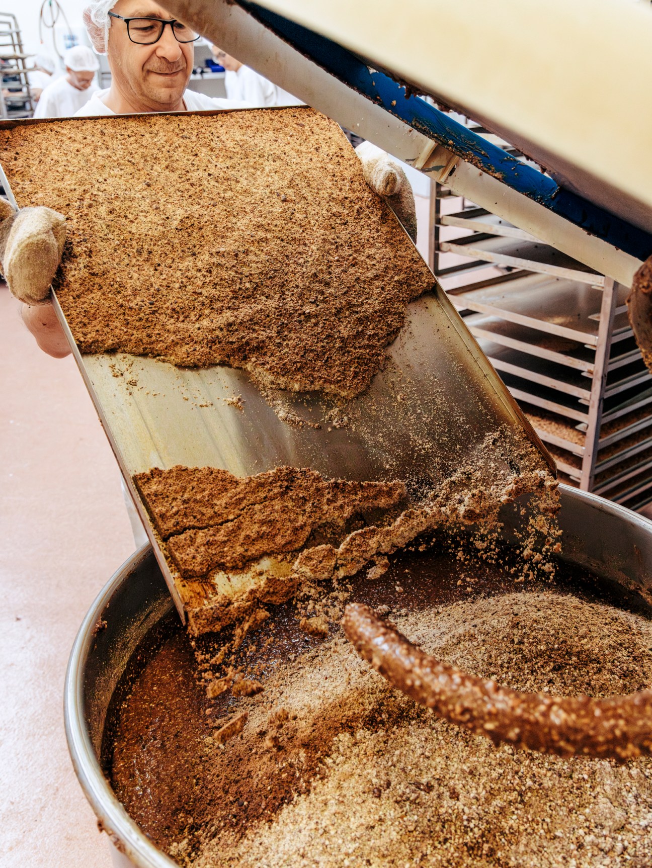 Man putting baking ingredients in a very large mixing bowl