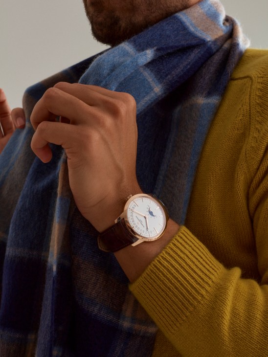 Person wearing rollneck jumper and scarf with luxury watch, displaying classic menswear styling