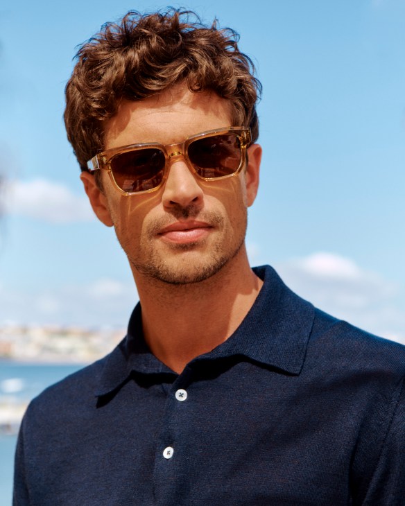 Man in white polo shirt and sunglasses against yellow wall