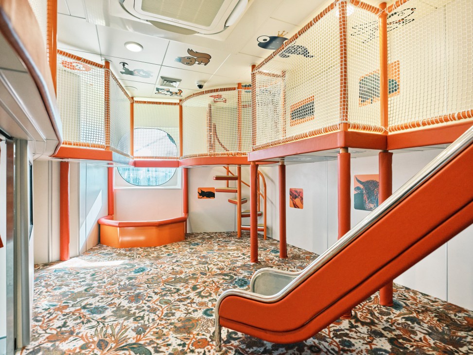 Colorful children's playroom aboard the Queen Beetle ferry with orange mesh barriers, slides, and patterned carpet