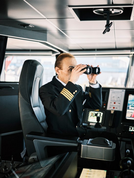 Captain Masaki Hidaka using binoculars on the bridge of the Queen Beetle ferry