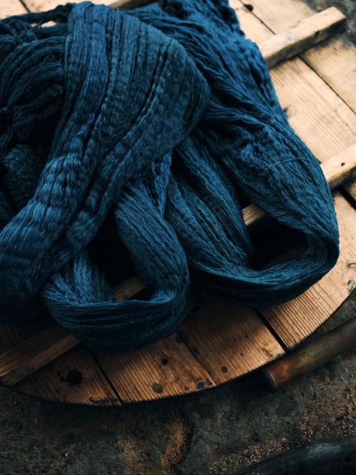 Bundles of deep blue indigo-dyed yarn laid out on wooden planks