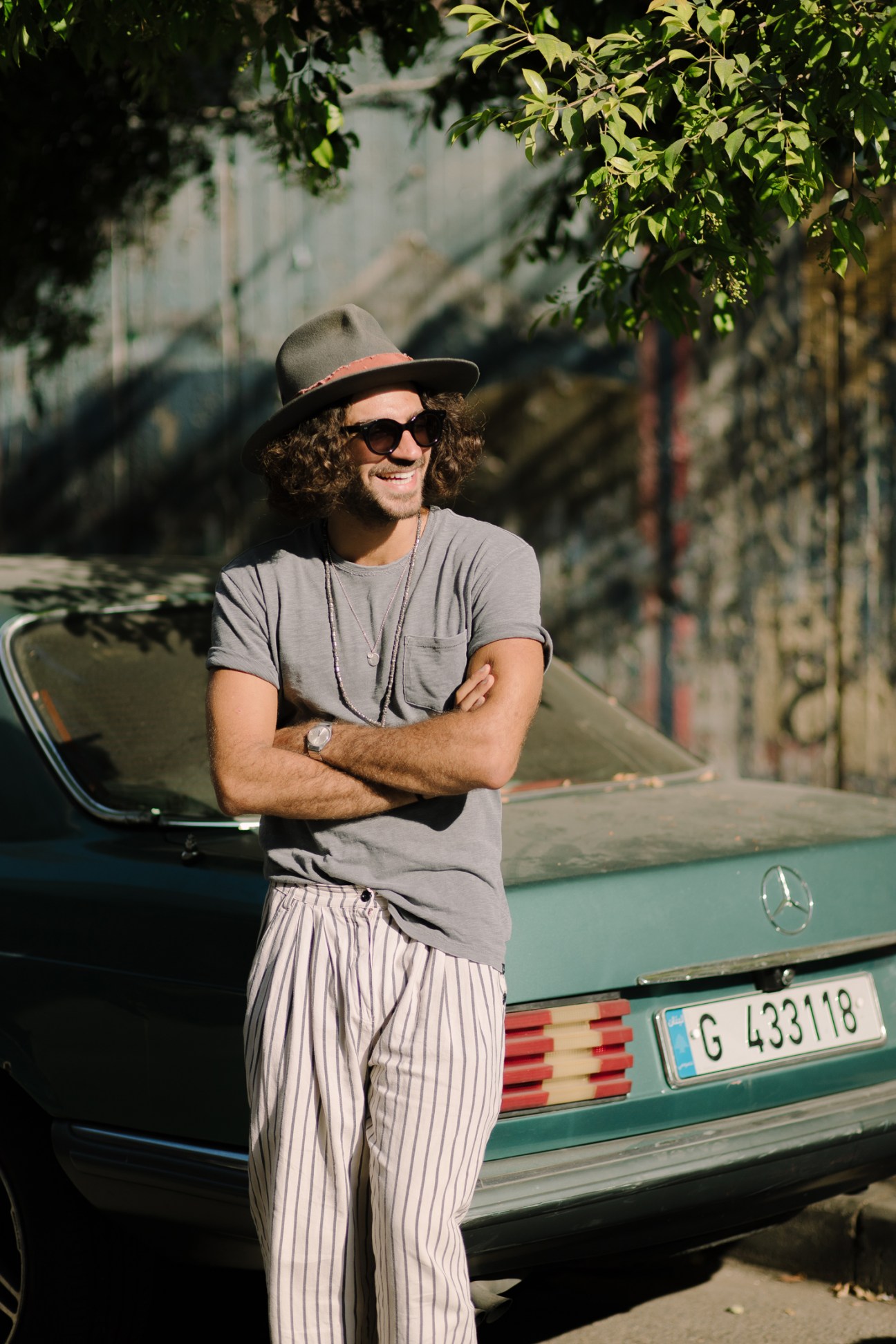 Co-owner Karl Hadife standing with arms crossed next to a vintage green Mercedes convertible