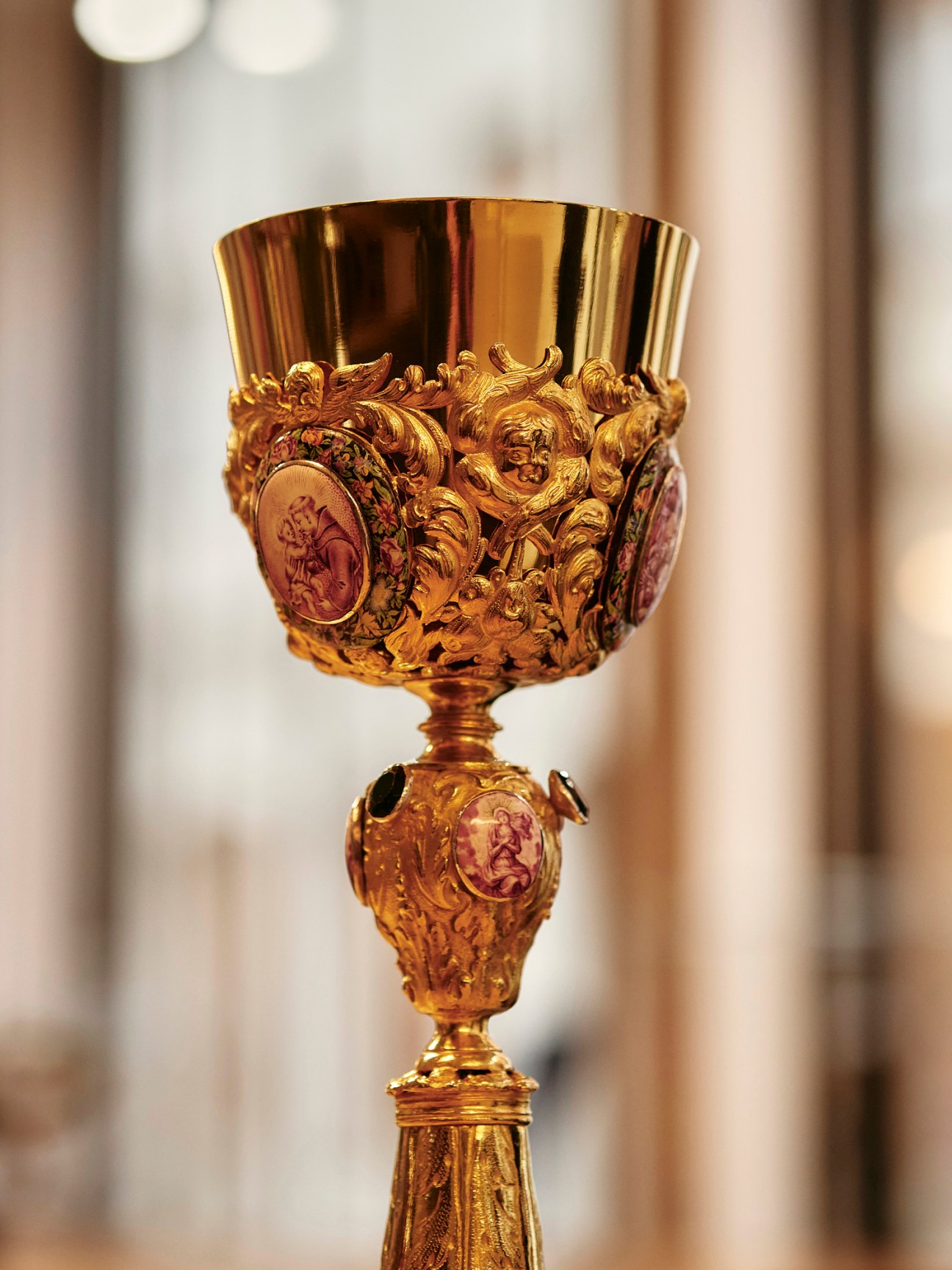 Ornate golden Catholic chalice with detailed religious reliefs and decorative elements