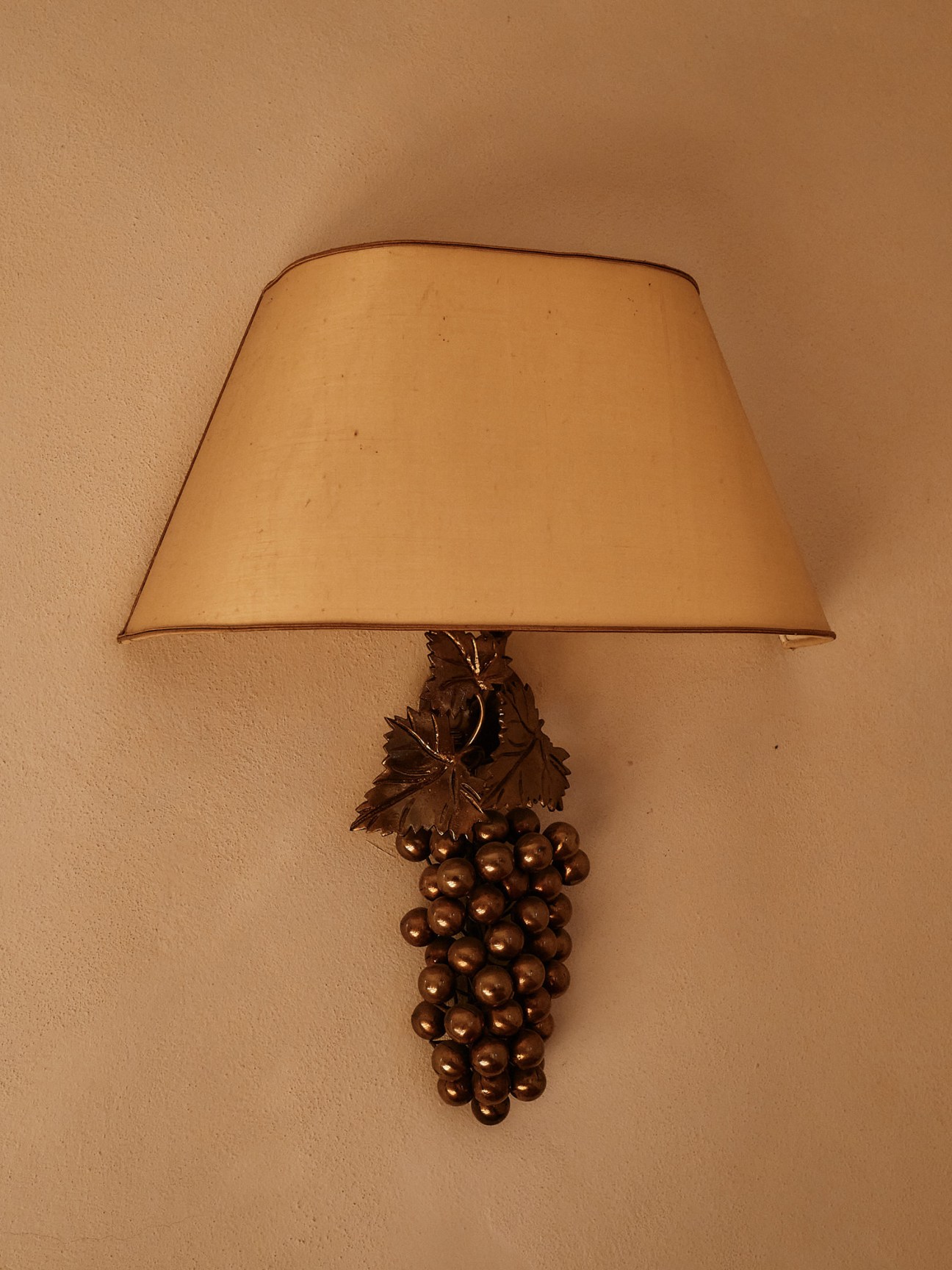 Wall sconce lamp with grape cluster design and cream lampshade