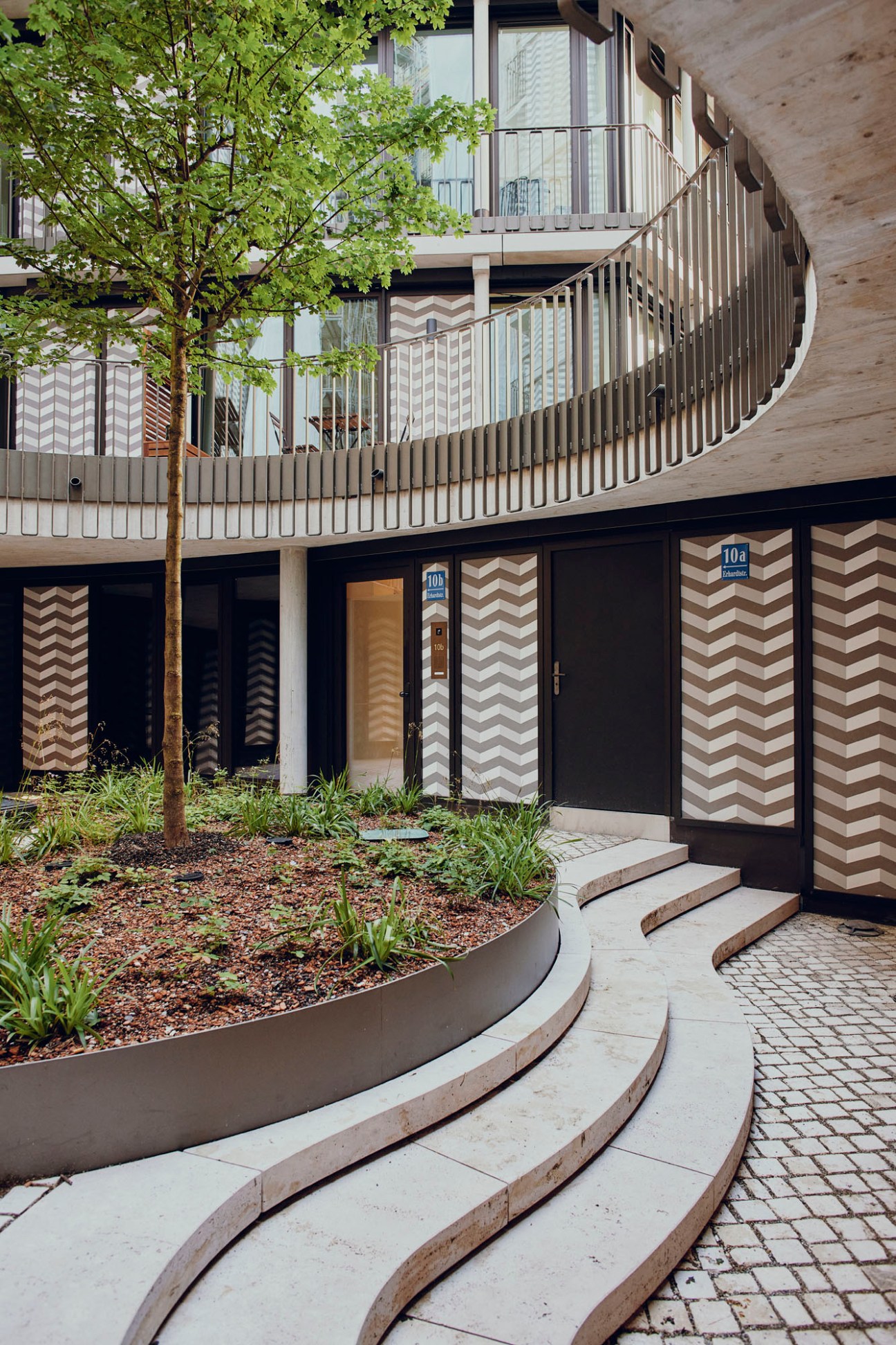 Modern apartment building with zigzag chevron pattern facade and curved balcony railings