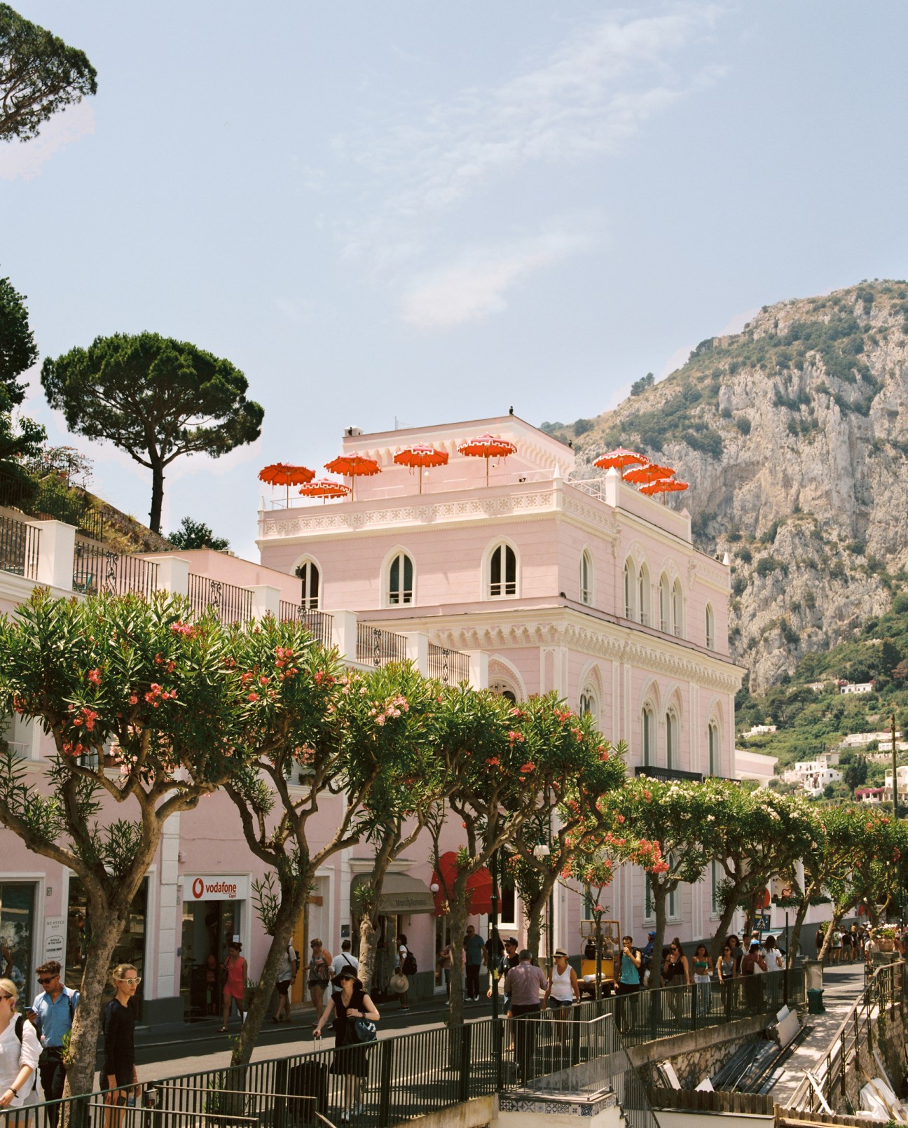 Il Capri Hotel terrace with orange umbrellas overlooking Mediterranean coastline and white buildings