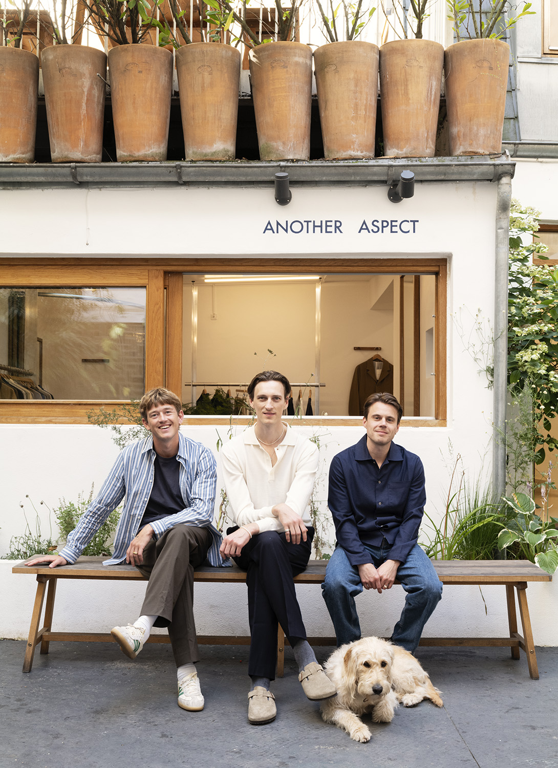 Anders Poulsen, Daniel Brøndt and Nicolaj Thomsen sitting on bench outside Another Aspect store in Copenhagen with dog