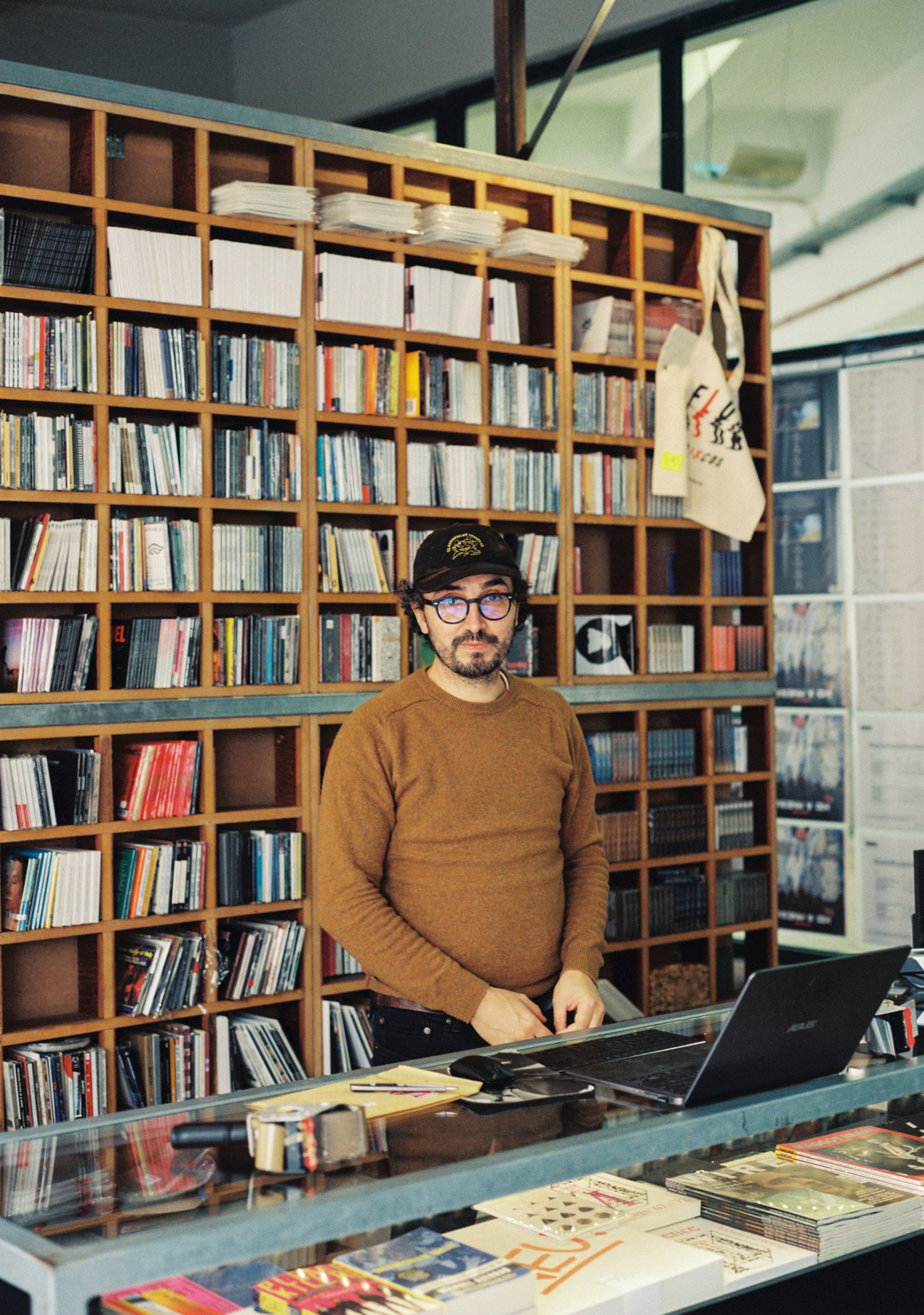 André from Flur Discos standing behind counter in record store with extensive vinyl collection on shelves