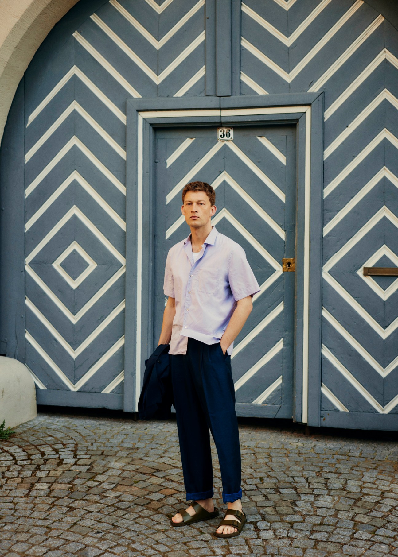 Model wearing light-coloured jacket and trousers with shirt and vest